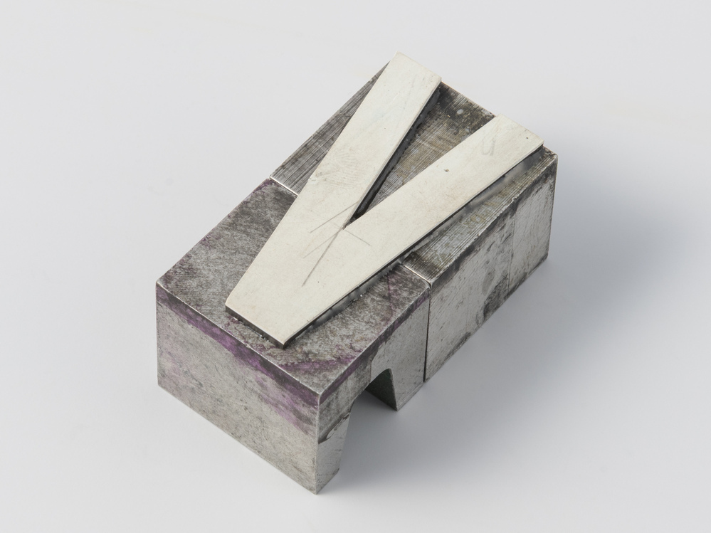 Drukvorm van snijplastic op lood in de vorm van een V