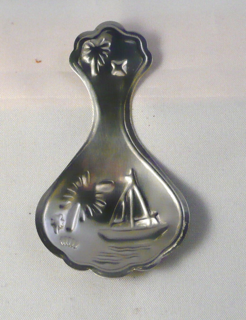 Metalen theeschep van de firma Insulinde Groningen