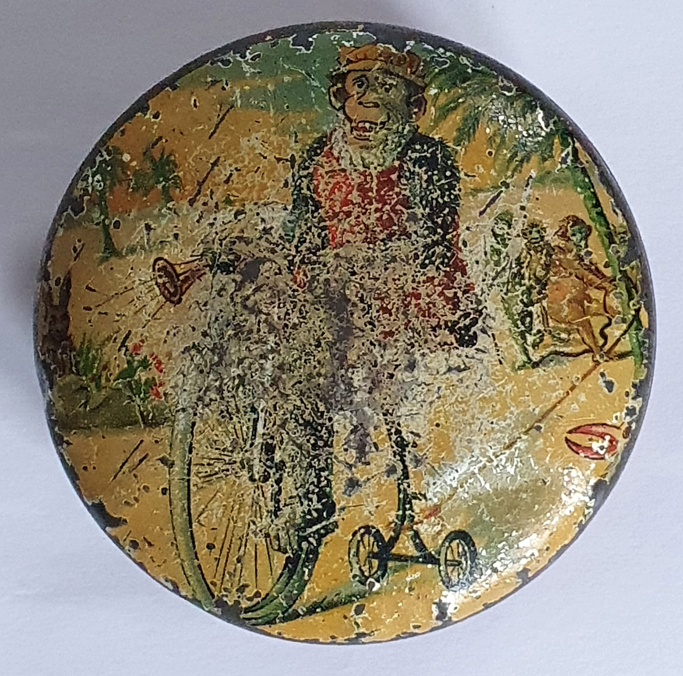 Pette, rond chocoladeblikje met aap op velocipede