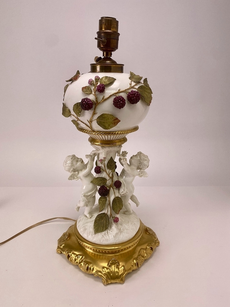 Staande bureaulamp met cherubijn-figuren en takken met bramen.