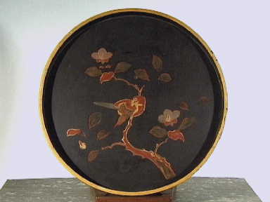 Rond dienblad van zwart gelakt hout met een décor in rood, goud en groen van een vogel op een tak.