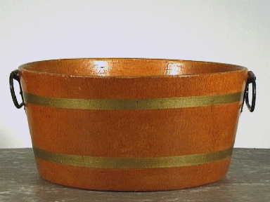 Rond afwasbakje van okerkleurig geperst papier mache met twee goudkleurige banden en twee zwart metalen handgrepen.