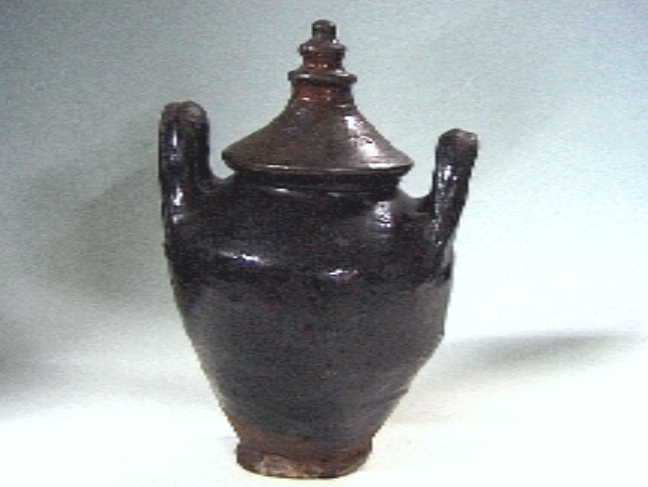 Donkerbruine voorraadpot (doofpot?) met deksel (schoorsteenkap?).