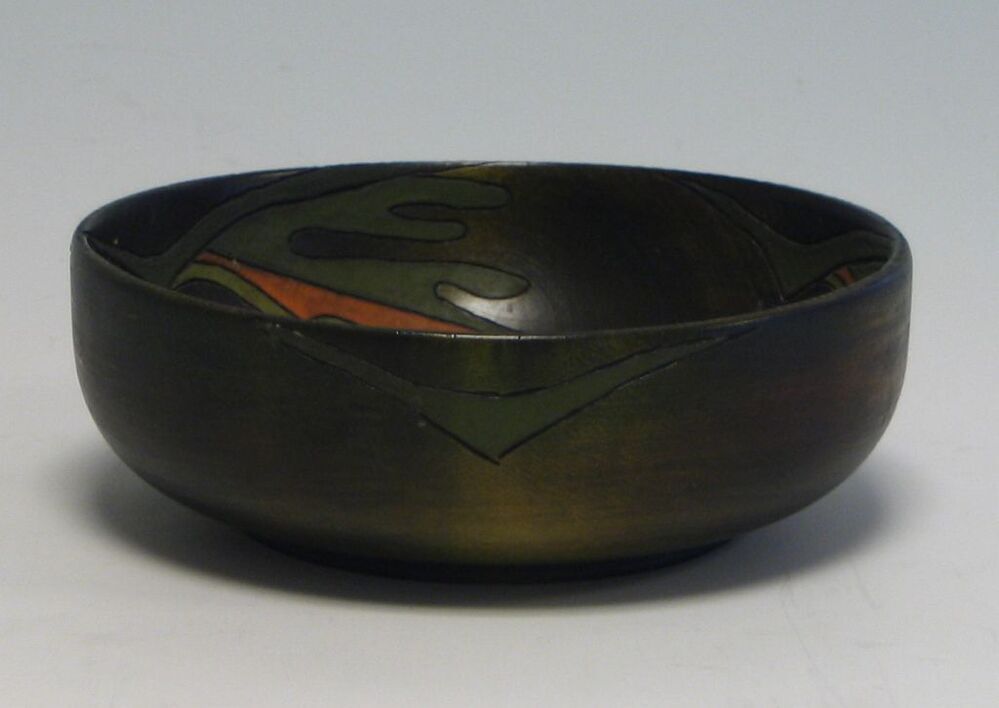 Groen houten kom met aan de binnenzijde drie deels oranje in gekleurde gestyleerde bladeren.