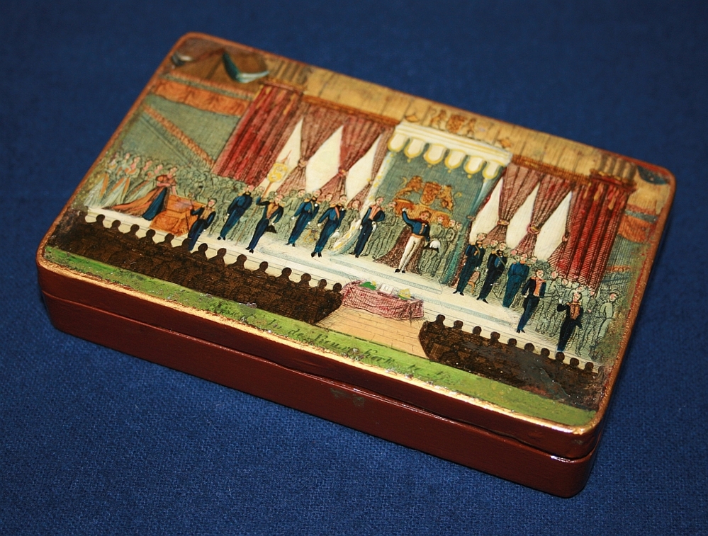 Rood beschilderde blikken tabaksdoos met op het deksel een miniatuur lijkstatieprent van de begrafenis van Koningin Wilhelmina van Pruisen op 26 oct.