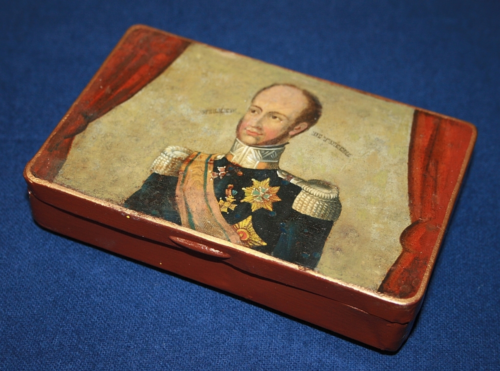 Rood beschilderde blikken tabaksdoos met op het deksel een miniatuur lijkstatieprent van de begrafenis van Koningin Wilhelmina van Pruisen op 26 oct.