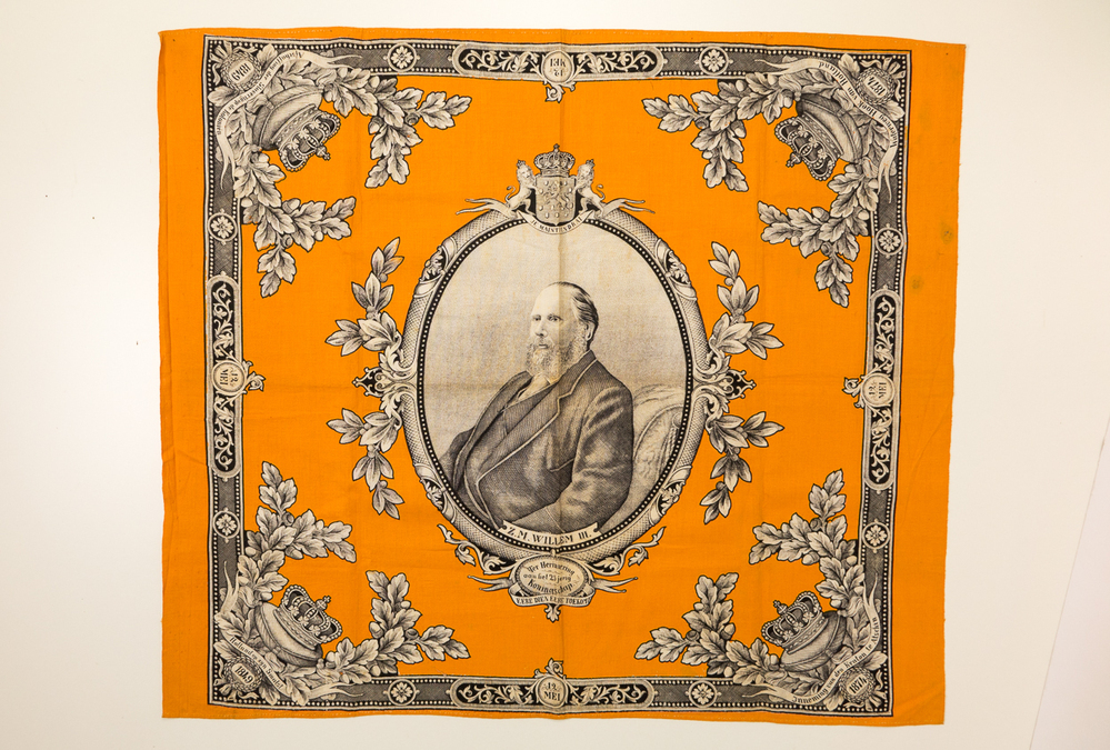 Doek, oranje/zwart/wit, met centraal in een ovaal een portret, heupstuk, van Willem III.