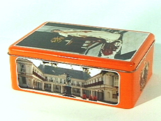 Koektrommel met hoofdkleur oranje. Op deksel koningin Beatrix in kroningsgewaad.