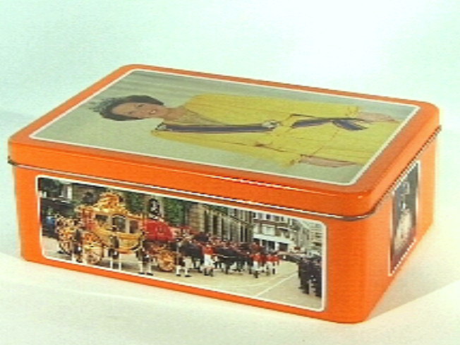 Koektrommel met hoofdkleur oranje. Op deksel heupportret van koningin Beatrix.