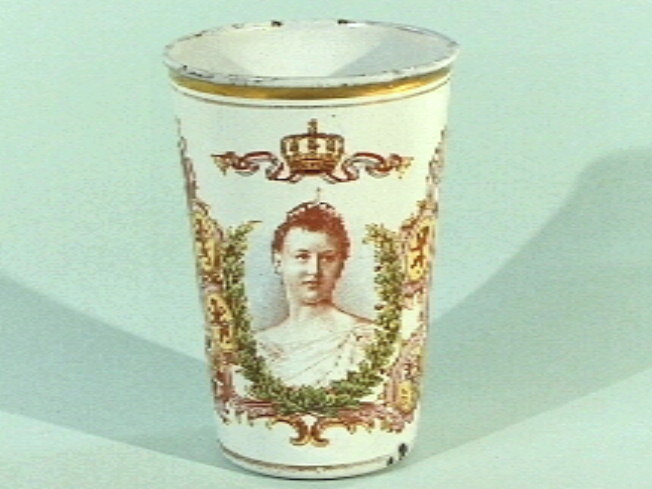 Gëemailleerde blikken beker, met op een witte ondergrond een ovaal portret van de jonge koningin Wilhelmina, een kroon, het koningswapen, en elf provinciewapens.