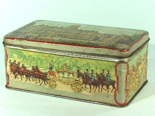 Blikken trommel met deksel. Op deksel Paleis op de Dam te Amsterdam,  op zijkanten de Gouden Koets, twe wapenschilden, paleis Soestdijk.