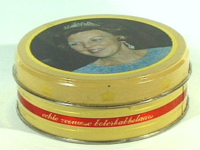 Rond blikken trommeltje voor boterbabbelaars  met op deksel busteportret van Koningin Beatrix met blauwe japon, diadeem en oorhanger.