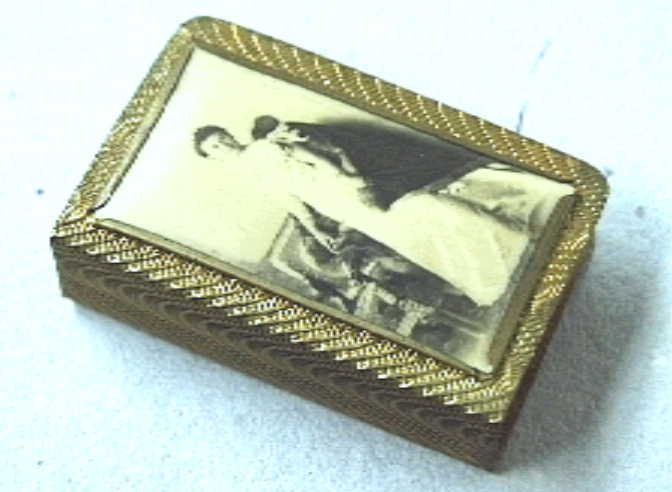 Houder voor lucifersdoosje ? met aan voorzijde een portret in zwart-wit van de jonge koningin Wilhelmina op 17-jarige leeftijd.