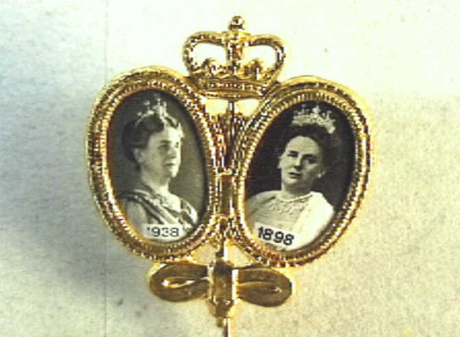 Speldje t.g.v. 40-jarige regeringsjubileum , met twee fotoportretjes in ovaal en daarboven een kroon.