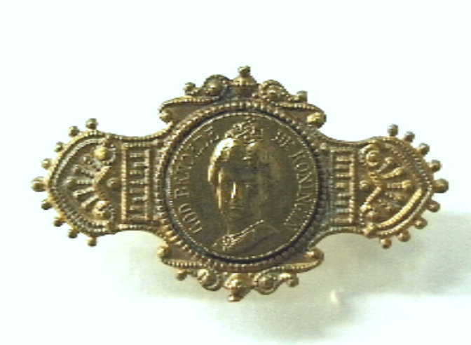 Speldje met busteportret van koning Wilhelmina in een cirkel, met aan beide zijden ornamenten.