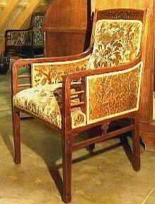 Mahoniehouten stoel met armleuningen en goudkleurige gebloemde bekleding.