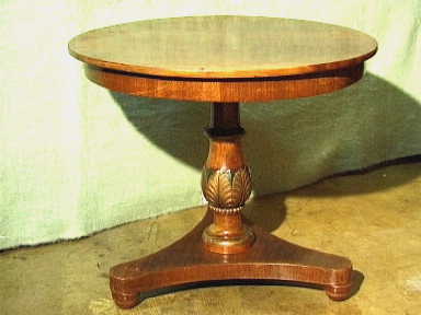 Ronde tafel op een brede poot met groen en goud ingekleurd houtsnijwerk .