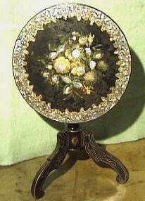 Rond zwart gelakt klaptafeltje (Spa-tafeltje?) waarbij het blad met een scharnier is verbonden met het onderstel.