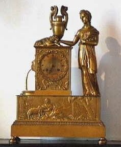 Vergulde pendule met vrouwenfiguren met een bloementuil in de arm.