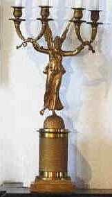 Vergulde kandelaber met vier armen en een gevleugelde vrouw .