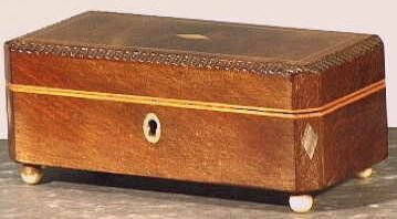 Rechthoekige bruine houten dekseldoos op vier bolvormige pootjes.