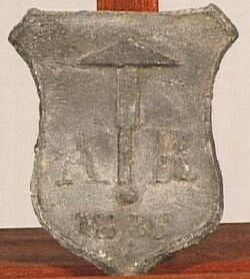 Loden schildje (trotseerloodje) met daarop een leidekkershamer .