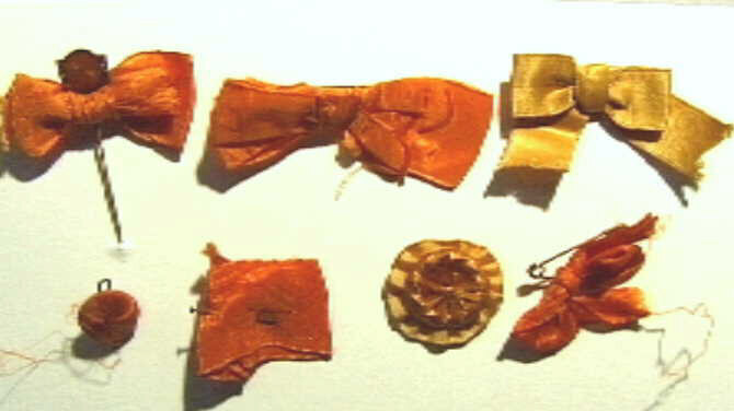 Zeven verschillende oranje strikje/lintjes, met een bevestigingsspeld.