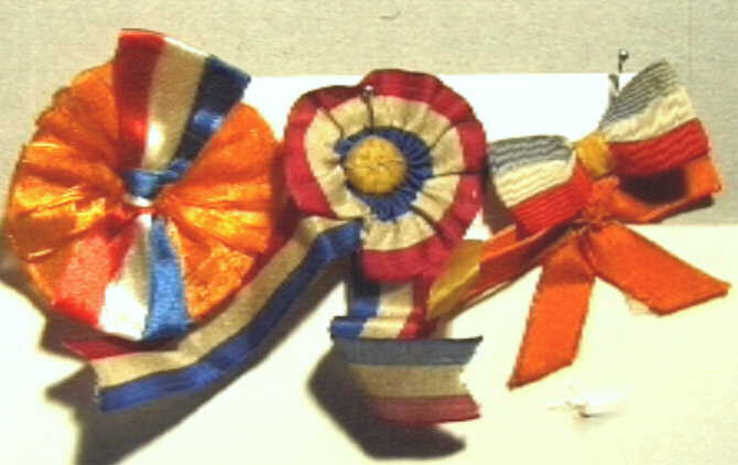 Drie corsages met een combinatie van oranje en rood-wit-blauw.