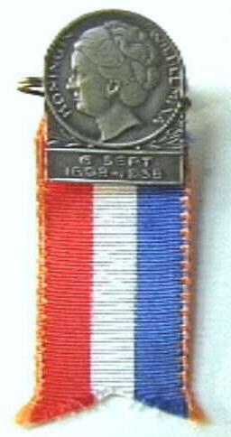 Speldje met portretkop naar links van koningin Wilhelmina,  met rood-wit-blauw lintje.