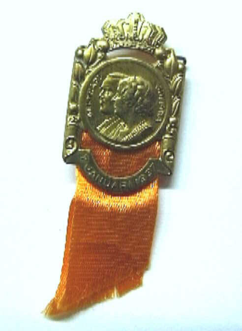 Corsage met busteportretten naar links van Bernhard en Juliana t.g.v. hun huwelijk in 1937. Met oranje lintje en speld aan de achterzijde.