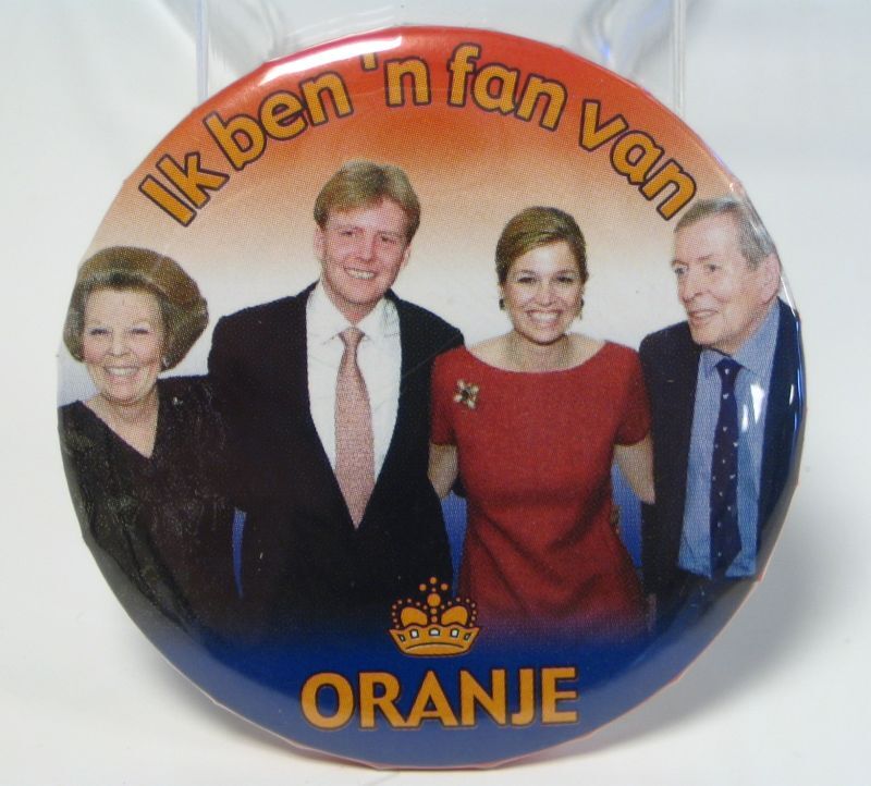 Ronde rood, wit, blauwe button met daarop een afbeelding van het elkaar omarmende viertal; Beatrix, Willem-Alexander, Maxima en Claus.