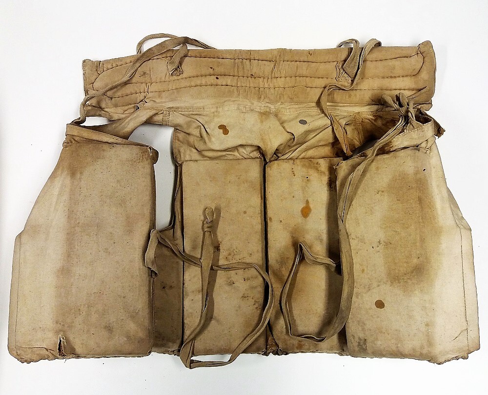 Reddingsvest van in zeildoek ingenaaide rechthoekige stukken kurk, in de vorm van een vest met een kraag en voorzien van banden ter bevestiging rond het lichaam