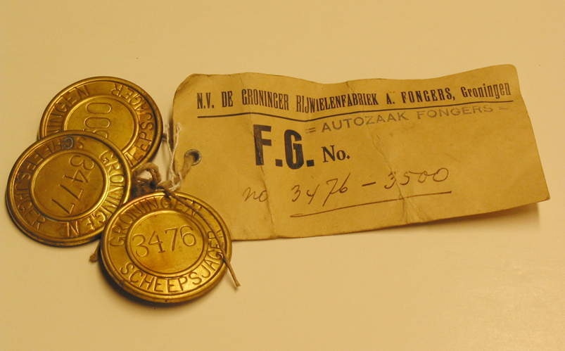 Drie aaneengebonden niet uitgegeven scheepsjagerspenningen met de nummers 3476, 3477, 3500 met aanhangend label van N.V. Gron. Rijwielfabriek A.Fongers Groningen.