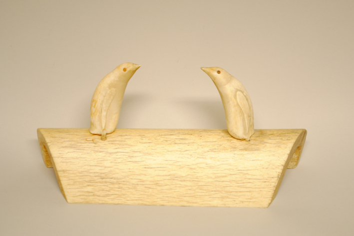 Twee pinguïns uit orkatanden, zittend op een sokkel van orkabeen