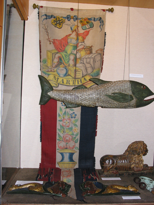 Feestwimpel van het beurtschip "Martha" dat voer van Rotterdam op Groningen met voorstelling van Mercurius, god van de koophandel, vervaardigd rond 1870 door F.H. Pijnappels.