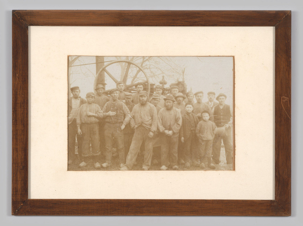 Foto van een groep mannen bij een machine