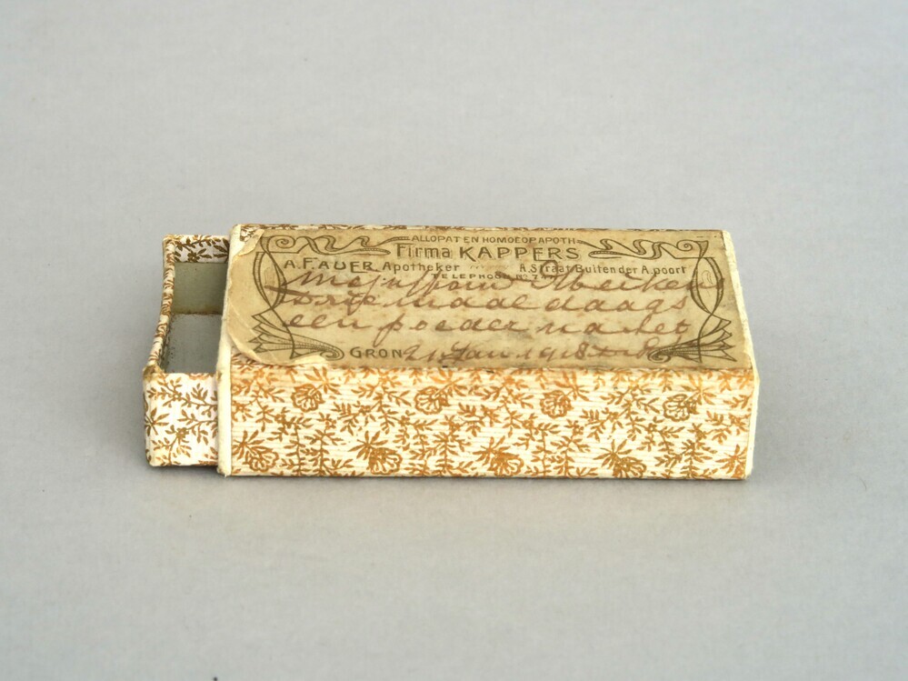 Luciferdoosje/medicijndoosje met daarop een sticker van de Firma Kappers/ A.F. auer Apotheker uit Groningen en opschrift: Mejuffrouw Heikens, drie maal daags een poeder ...(onleesbaar woord)