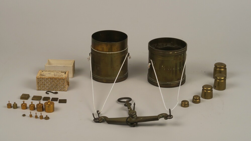 Koperen weegschaal met een aantal gewichten van verschillend formaat