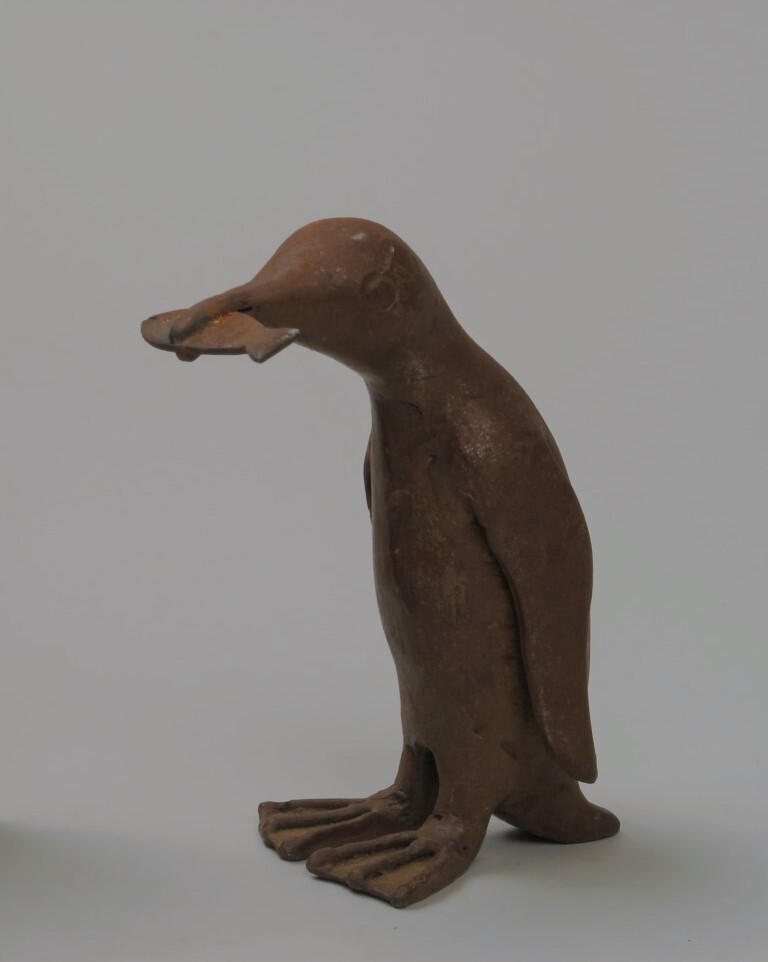 Metalen pinguïn met een vis in zijn bek