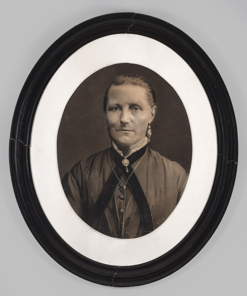 Portretfoto, achter glas, ovale lijst, voorstellende een vrouw