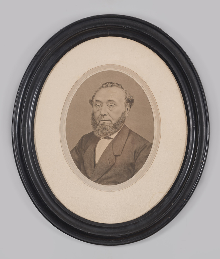 Portretfoto, achter glas, in ovale lijst, voorstellende man met baard