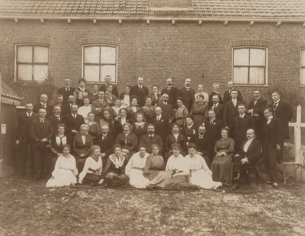 Foto van een gezelschap bij een schoolgebouw (?), ingelijst