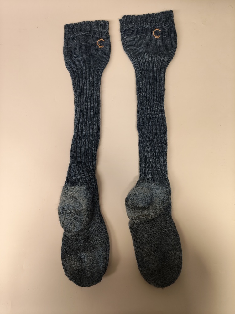 Een paar blauwe wollen sokken die meerdere malen gestopt zijn.