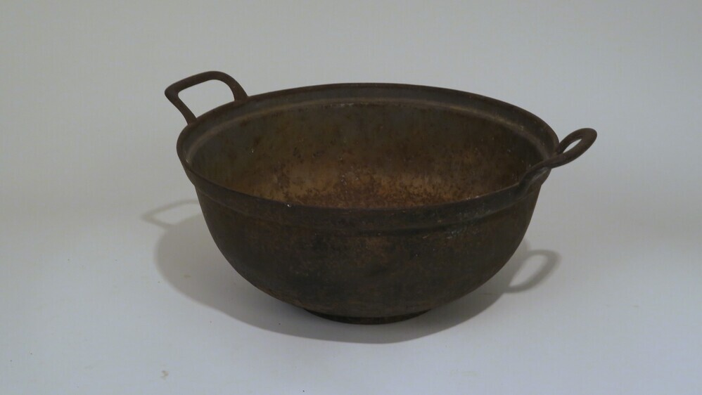 Grote gietijzeren pan met twee handgrepen. De pan is mooi gevormd en heeft een standring van ongeveer 9 mm hoog. De buitenkant is zwart gelakt, de binnenkant donkergrijs.