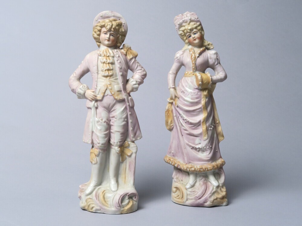 2 beeldjes van man en vrouw in roze/paars outfit