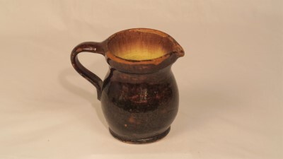 Bruin geglazuurde schenkkan met vlakke bodem uit de tweede helft van de negentiende eeuw