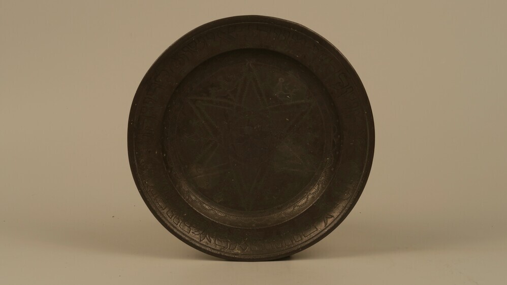 Poerimbord (tin). Cirkel waarin 8-armige ster, daaromheen 6-armige ster. Langs de rand van het bord Hebreeuwse tekst. Achterzijde, 3 stempels naast, deels over elkaar van persoon met weegschaal en springend hert