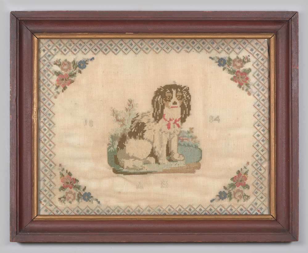 Borduurwerk, in lijst, achter glas, voorstellende een hond