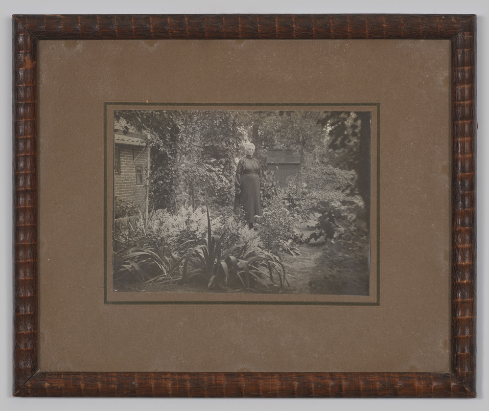 Zwart wit foto van een oudere vrouw in een achtertuin