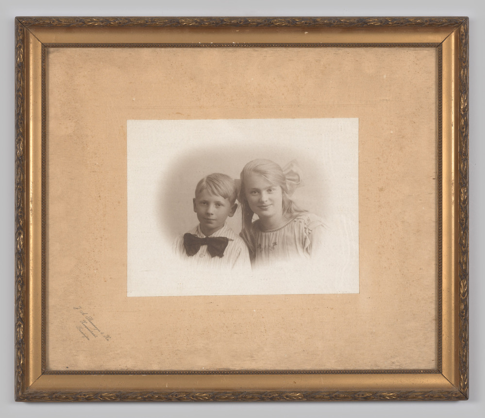 Portretfoto, ingelijst, achter glas, voorstellende een jongen en een meisje